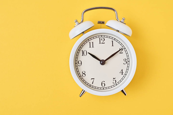 Reloj despertador retro blanco sobre fondo amarillo con espacio para copiar. Concepto de tiempo - Foto, imagen