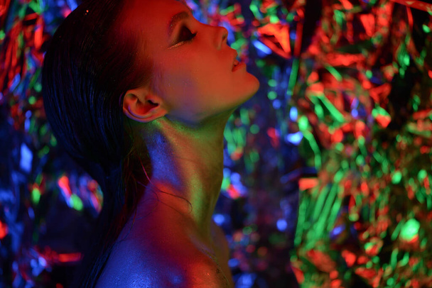 Kobieta modelka tańcząca w neonowym świetle, dyskotekowy klub nocny. Piękna tancerka model dziewczyna kolorowe jasne fluorescencyjny makijaż, malowana skóra, Body Art design dyskoteki. Promieniowanie ultrafioletowe, UV, barwny makijaż - Zdjęcie, obraz
