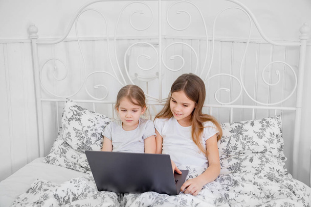 sisters study on computer online at home bed. - Φωτογραφία, εικόνα