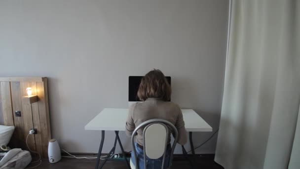 Masada oturan ve bilgisayarla çalışan bir kızın arka görüntüsü. Yakın plan. - Video, Çekim