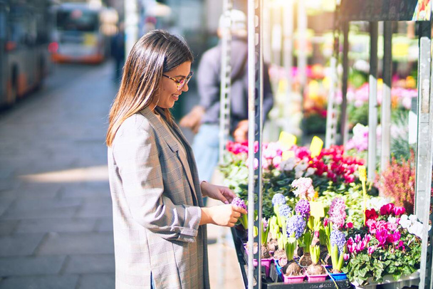 Young beautiful woman smiling happy and confident. Standing with smile on face at florist - Foto, Imagen