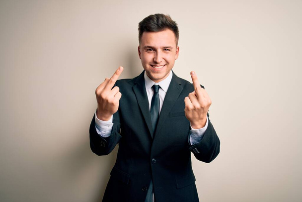 Young handsome business man wearing elegant suit and tie over isolated background Showing middle finger doing fuck you bad expression, provocation and rude attitude. Screaming excited - Foto, afbeelding