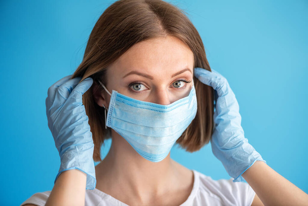 Nurse or doctor with face mask and gloves. Health care, surgery. Close up portrait of young caucasian woman model on blue background - Fotografie, Obrázek