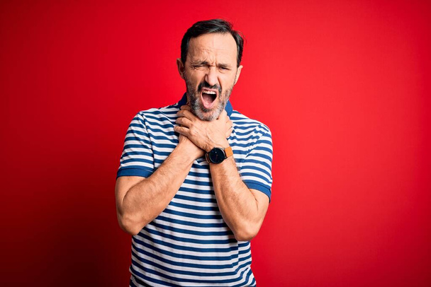 Middle age hoary man wearing casual striped polo standing over isolated red background shouting and suffocate because painful strangle. Health problem. Asphyxiate and suicide concept. - Photo, Image