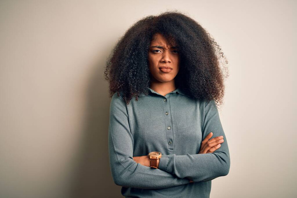 Afro saçlı, genç ve güzel bir Afro Amerikalı kadın izole edilmiş arka planda duruyor şüpheci ve gergin, yüzünde çapraz kollarla onaylamayan bir ifade var. Negatif kişi. - Fotoğraf, Görsel