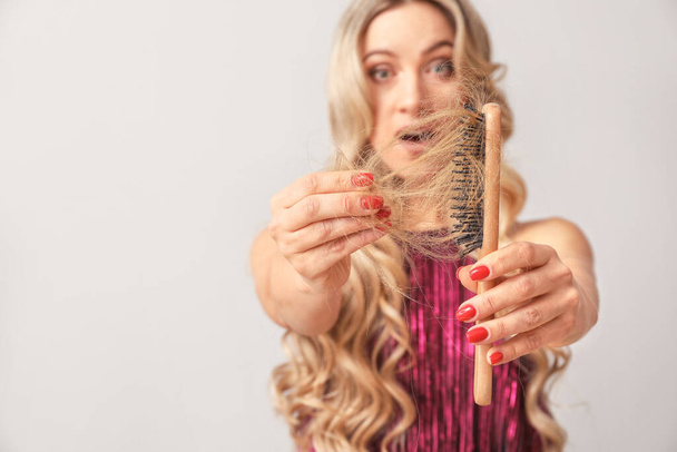 Aggódó nő hajhullás probléma a könnyű háttér - Fotó, kép