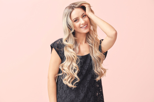 schöne junge Frau mit lockigem Haar auf farbigem Hintergrund - Foto, Bild