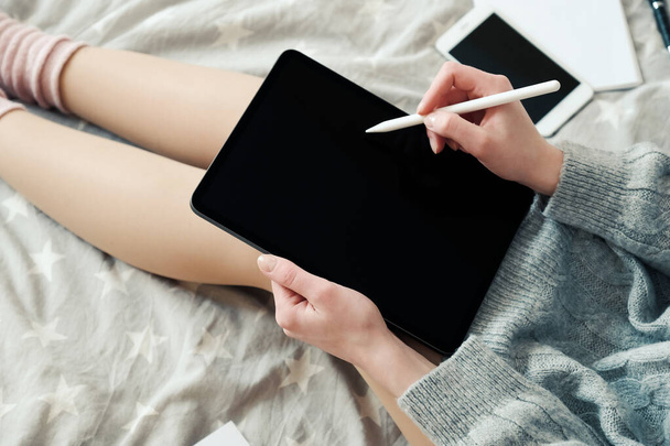Young female freelancer graphic designer working with drawing digital tablet in bed at home, close-up view. Working home, stay safe, distance education concept. Hygge, cozy style - Photo, Image