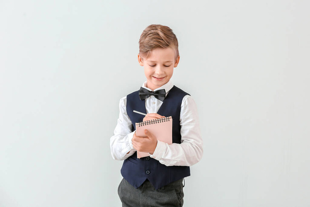 Cute little waiter with notebook on light background - Photo, image