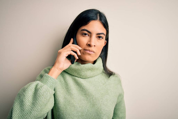 Mujer hispana hermosa joven teniendo una conversación hablando en el teléfono inteligente con una expresión segura en la cara inteligente pensando en serio
 - Foto, Imagen