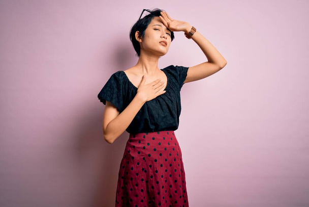 Jeune belle fille asiatique portant une robe décontractée debout sur fond rose isolé Toucher le front pour la maladie et la fièvre, grippe et rhume, virus malade
 - Photo, image