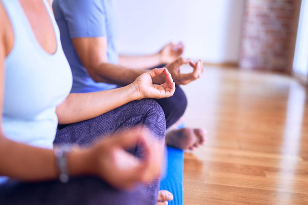 Schönes sportliches Paar mittleren Alters sitzt auf Matte und praktiziert Yoga und posiert Lotus im Fitnessstudio - Foto, Bild