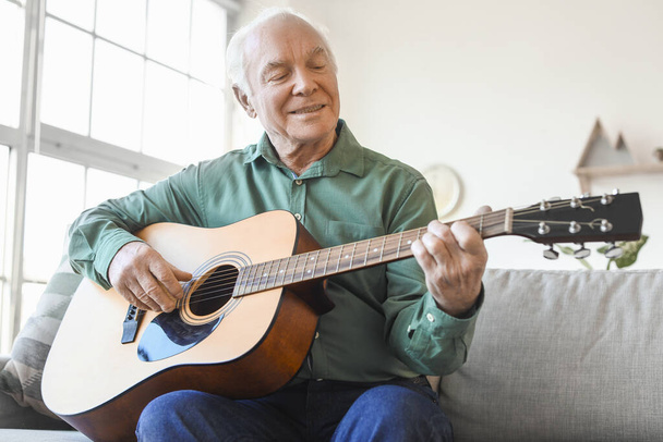 Starszy mężczyzna gra na gitarze w domu - Zdjęcie, obraz