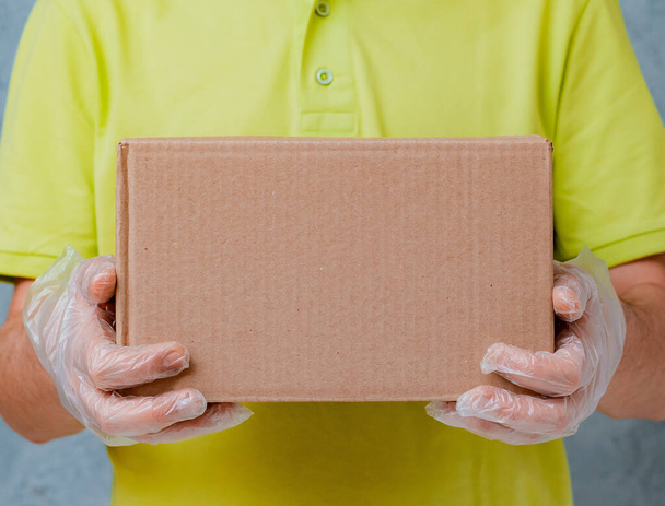 El mensajero sostiene cajas de cartón en guantes desechables. Entrega sin contacto durante el período de cuarentena del coronavirus
 - Foto, imagen