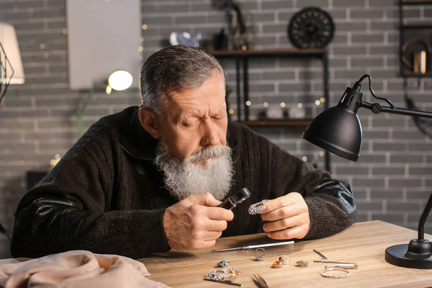 Jeweller examining adornment in workshop - Foto, imagen