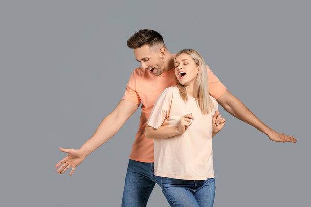 Happy dancing young couple on grey background - Photo, Image