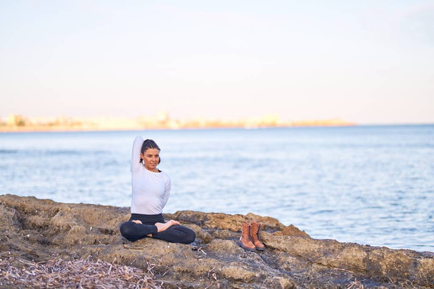 Joven hermosa deportista practicando yoga. Entrenador estirándose en la playa
 - Foto, imagen
