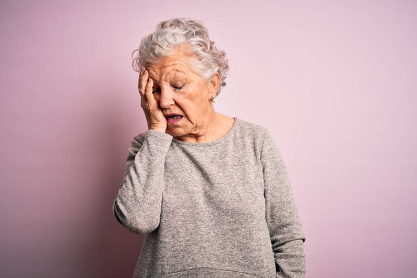 Senior mooie vrouw draagt casual t-shirt staan over geïsoleerde roze achtergrond geeuwen moe bedekken half gezicht, oog en mond met de hand. Gezichtspijn in pijn. - Foto, afbeelding