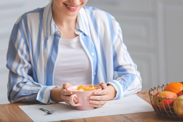 Νεαρή γυναίκα τρώει νόστιμο γιαούρτι στην κουζίνα - Φωτογραφία, εικόνα