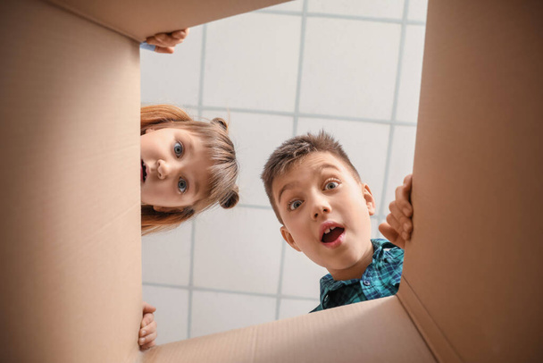 Curious children looking inside cardboard box, bottom view - Photo, Image