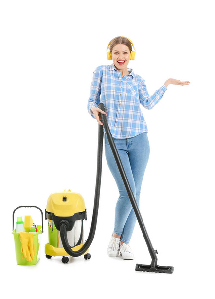 Young woman with vacuum cleaner listening to music on white background - Foto, Imagen