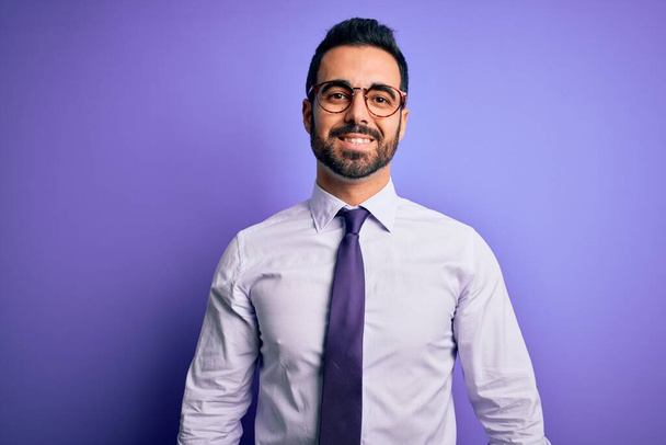 Handsome businessman with beard wearing casual tie and glasses over purple background with a happy and cool smile on face. Lucky person. - Foto, Bild