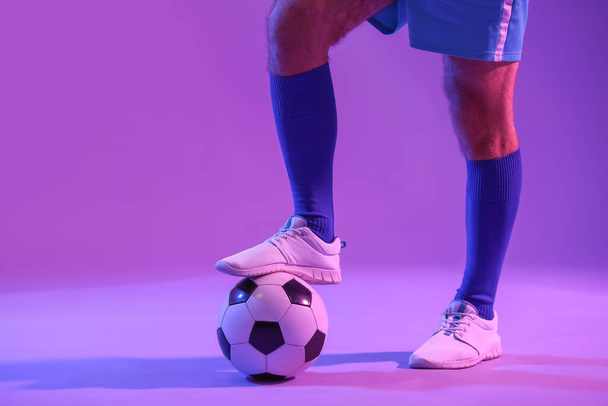 Πόδια του ανδρικού ποδοσφαιριστή στο φόντο χρώμα - Φωτογραφία, εικόνα