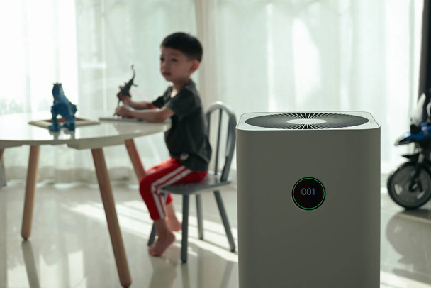 Luftreiniger im Wohnzimmer mit Kind, das im Haus spielt - Foto, Bild
