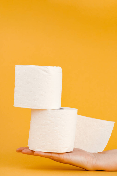 A roll of toilet paper in a woman's hand on a yellow background. - Photo, Image
