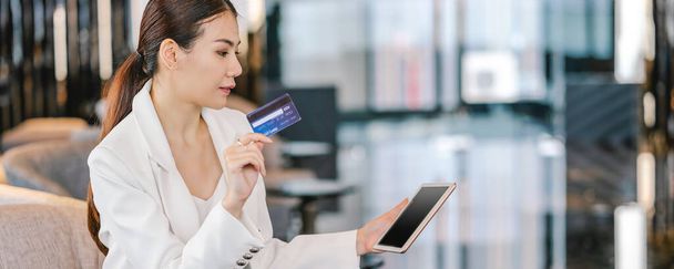 Banner, web page or cover template of Portrait Asian woman using credit card with technology tablet for online shopping in lobby or working space, technology money wallet and online payment concept - Photo, Image