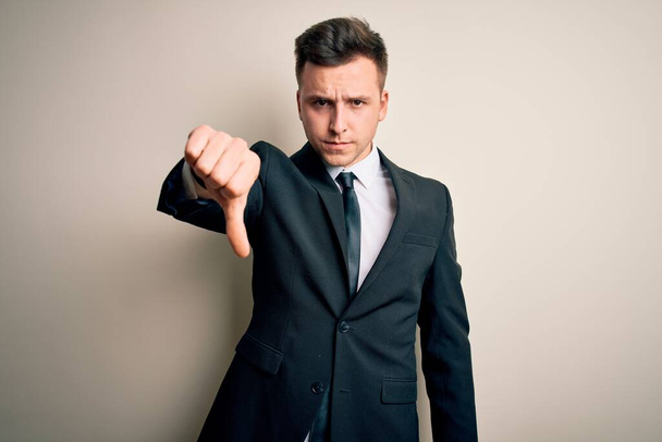 Young handsome business man wearing elegant suit and tie over isolated background looking unhappy and angry showing rejection and negative with thumbs down gesture. Bad expression. - Photo, Image