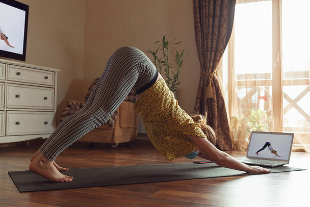 Sporty young woman taking yoga lessons online and practice at home while being quarantine - Photo, Image