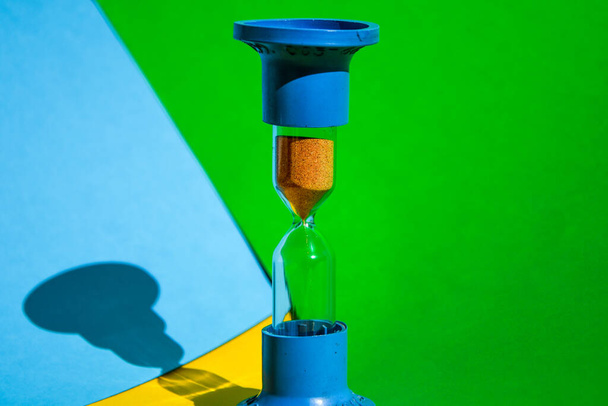 Hourglass colored background, copy space for text, Hourglass shows that time is running out, sand glass, The concept of time, delay, morning rise, the appointed meeting - Photo, Image