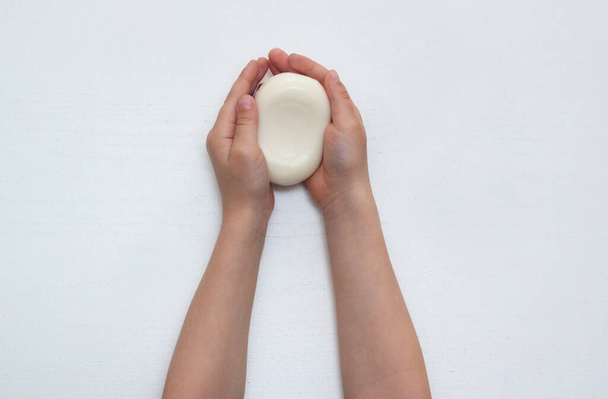 Child hands holding white soap bar. Plain white background. Isolated. Healthy lifestyle concept. - Photo, image