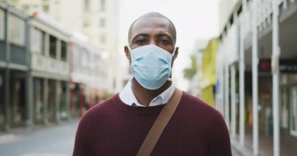 Portrait of an African American man out and about in the city streets during the day, wearing a face mask against air pollution and covid19 coronavirus. - Filmagem, Vídeo
