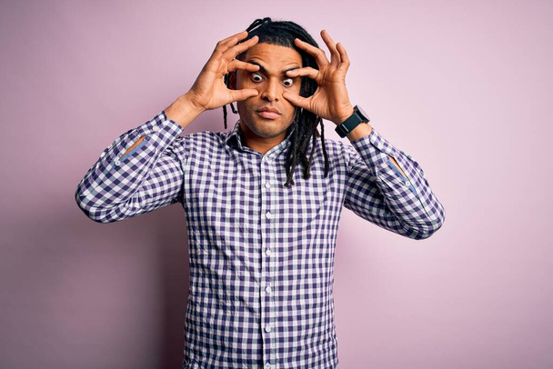 Young handsome african american afro man with dreadlocks wearing casual shirt Trying to open eyes with fingers, sleepy and tired for morning fatigue - Photo, Image
