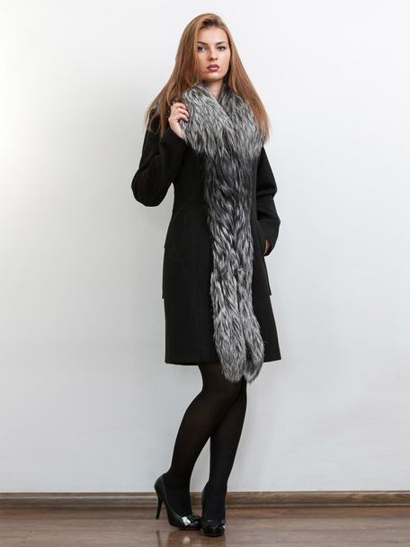 Slim model posing in black coat with natural fur collar - Foto, afbeelding