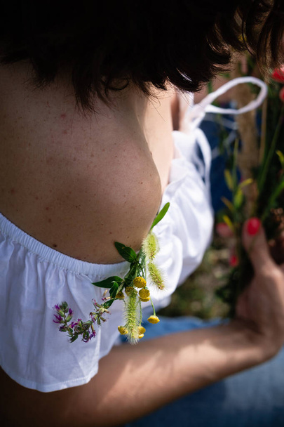 Naked female shoulder with moles decorated with a small bouquet of field herbs and flowers. Be gentle in the female body. - Photo, Image