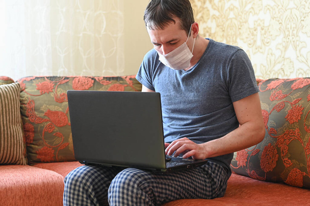 Άνθρωπος με φορητό υπολογιστή στο κρεβάτι στην κρεβατοκάμαρα. Εργασία από το σπίτι κατά τη διάρκεια Coronavirus Covid-19. Η έννοια της καραντίνας και της απομόνωσης. Μείνε σπίτι.. - Φωτογραφία, εικόνα