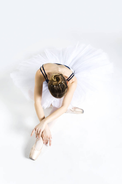 Νεαρή μπαλαρίνα που εξασκείται σε κινήσεις μπαλέτου στο στούντιο - Φωτογραφία, εικόνα