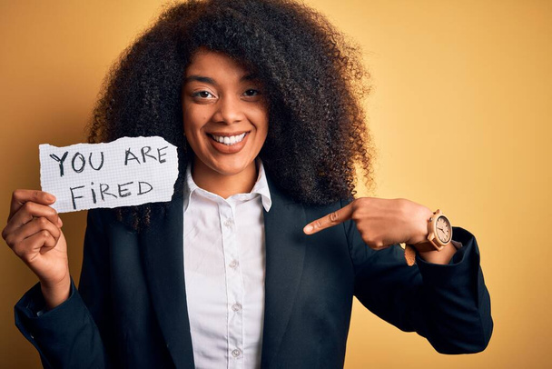 Африканский американский бизнес босс женщина с афроволосами держа вас уволены бумаги для увольнения с удивлением лицо указывая пальцем на себя
 - Фото, изображение