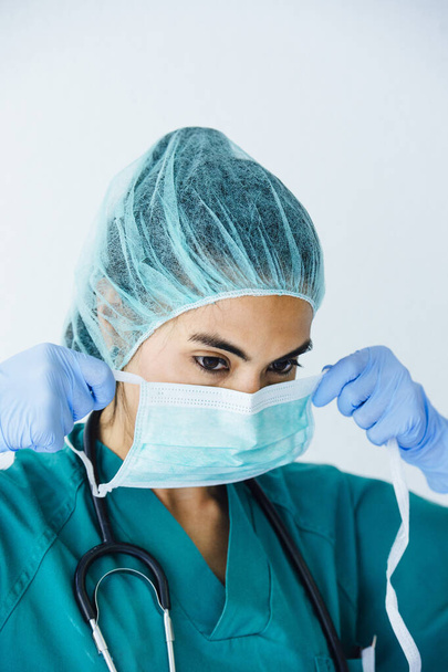 Verpleegster zet beschermend masker op - Foto, afbeelding