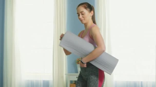 Mujer joven está esparciendo alfombra de fitness para hacer ejercicio
 - Imágenes, Vídeo