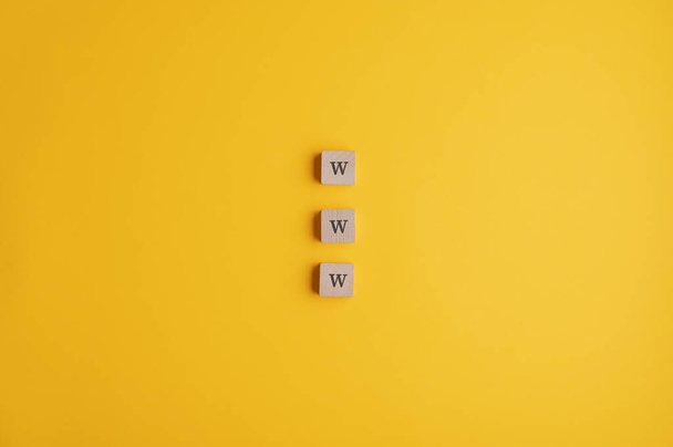 Three wooden blocks reading a www sign placed over yellow background with plenty of copy space. - Фото, зображення