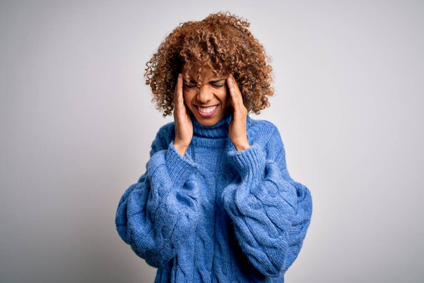 Joven mujer afroamericana hermosa con suéter de cuello alto sobre fondo blanco con la mano en el dolor de cabeza porque el estrés. Dolor de migraña
. - Foto, imagen