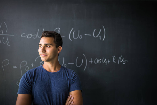 Students in a classroom - handsome student solving a math problem on a blackboard during math class - Photo, image