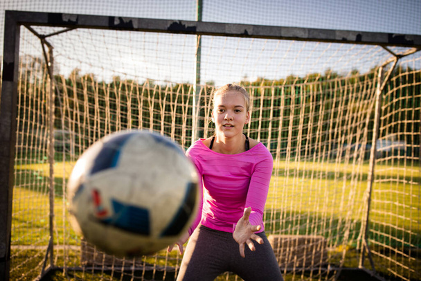 Teen female goalie catching a shot during a soccer game - Photo, image