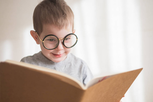 Bonito menino criança lendo um livro em óculos. Pré-escolar inteligente. Voltar ao conceito de escola
 - Foto, Imagem
