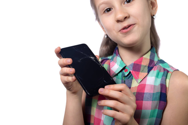 Cute little girl with broken smartphone on white background - Foto, afbeelding