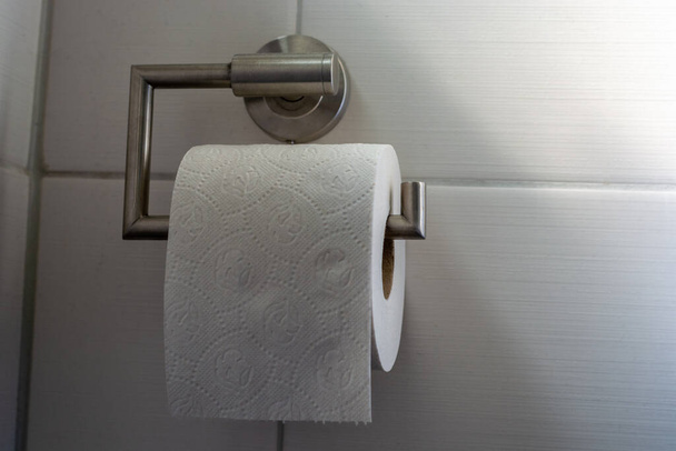 Rollo de papel higiénico completo colgando en el baño como primer plano
 - Foto, imagen